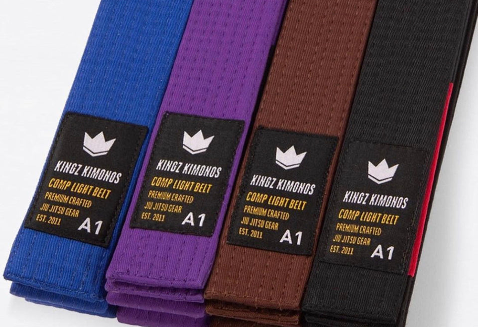 Kingz BJJ belts in rank order — blue, purple, brown and black