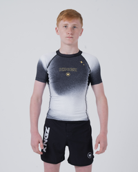 Kingz Galaxy Youth Rashguard Black White - Full Body Front View Teen Boy Athlete Short Sleeve Black White Ombre Galaxy Pattern Gold Star KINGZ Gold Text Crown Logo Black Shorts Kids BJJ