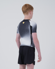 Kingz Galaxy Youth Rashguard Black White - Full Body 3/4 Back View Left Side Teen Boy Athlete Short Sleeve Galaxy Ombre Pattern Gold Crown Logo Left Shoulder KINGZ Text Shorts Kids Youth