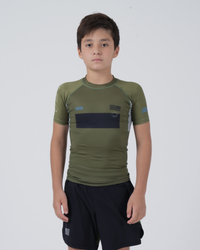Kingz Trooper Youth Rashguard Military Green - Full Body Front View Young Boy Athlete Short Sleeve Olive Green Black Chest Band Flag Patches Gray Side Panels Black Shorts Kids BJJ