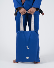 Kingz The ONE V2 Women's Jiu Jitsu Gi Blue - Close-Up Front View Female Athlete Blue Gi White Contrast Trim Kingz Logo Bag Brown Belt Visible BJJ Gi Training [color:Blue]
