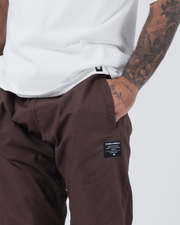 Kingz Casual Rip Stop Gi Pant - Brown - Close-Up Detail View Tattooed Male Hand Pocket Kingz Kimonos Label Earthy Brown Rip Stop Fabric BJJ Gi Training Apparel [color:Earthy brown]