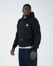 Black BJJ hoodie front three-quarter view on adult male model showing crown chest logo and relaxed fit