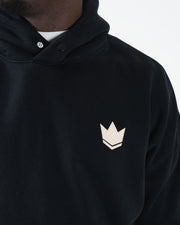 Black BJJ hoodie chest detail closeup of tan crown logo with snap button collar and dual panel neckline
