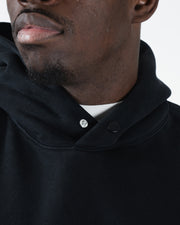 Black BJJ hoodie neckline closeup showing metal snap button closure and dual panel collar construction