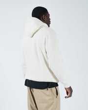 Beige BJJ hoodie rear side profile on adult male model showing relaxed drape and hood construction