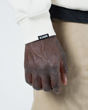 Beige BJJ hoodie cuff detail closeup showing ribbed sleeve cuff with woven Kingz label tag and stitching