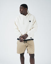 Beige BJJ hoodie side profile view on adult male model showing box fit silhouette and ribbed hem drape