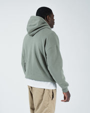 Dark forest green BJJ hoodie rear side profile on adult male model showing relaxed drape and hood detail