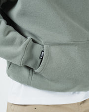 Dark forest green BJJ hoodie hem detail closeup showing woven Kingz label ribbed cuff and pocket edge