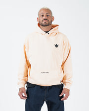 Peach BJJ pullover hoodie front view on adult male model with dark crown logo and motion pocket script