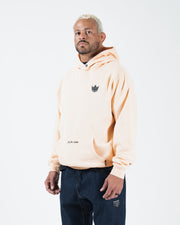 Peach BJJ hoodie front three-quarter view on adult male model showing crown chest logo and relaxed fit