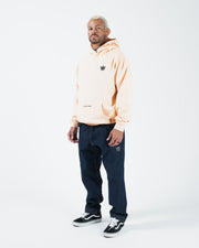 Peach BJJ hoodie full body lifestyle shot with adult male model in jeans and black sneakers standing
