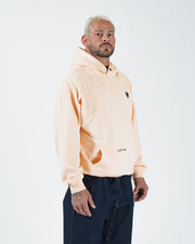 Peach BJJ hoodie side profile view on adult male model showing relaxed silhouette and ribbed cuff drape