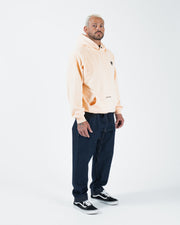 Peach BJJ hoodie full body side profile lifestyle shot with adult male model in jeans and black shoes
