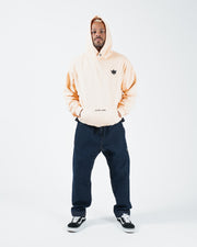 Peach BJJ hoodie full body front shot with adult male model wearing hood up and hands in front pocket