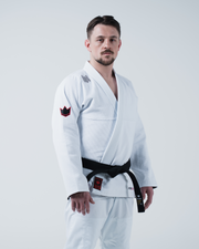 Kingz Ultralight 2.0 BJJ Gi White - 3/4 Side View Male Athlete Standing Complete White Gi Set Red Sleeve Crown Logo Patches Black Belt