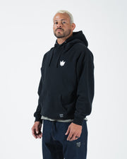 Black BJJ hoodie front standing view on adult male model showing 320 GSM fleece and layered casual look