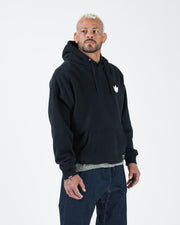 Black BJJ hoodie front three-quarter view on adult male model highlighting crown logo and relaxed drape