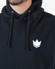 Black BJJ hoodie chest closeup of white crown emblem logo with drawstring hood cords and soft fleece
