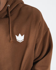 Chestnut brown BJJ hoodie chest closeup of white crown emblem logo and drawstring hood cord detail