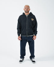 Black BJJ zip up hoodie full body lifestyle shot with adult male model in dark jeans and black sneakers