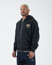 Black BJJ zip up hoodie front three-quarter view on adult male model highlighting flag logo and zipper