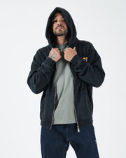 Black BJJ zip up hoodie front view on adult male model wearing hood up over grey tee holding the collar