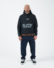 Black BJJ hoodie full body lifestyle shot with adult male model in relaxed streetwear styling stance