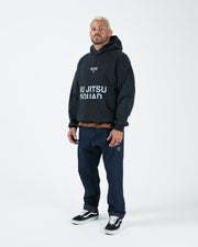 Black BJJ hoodie full length angled lifestyle shot with adult male model showing casual outfit pairing
