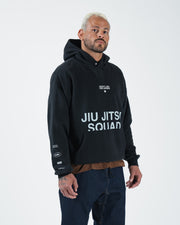 Black BJJ hoodie front three-quarter view on adult male model with Jiu Jitsu Squad print and sleeve logos