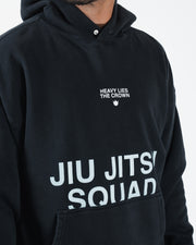 Black BJJ hoodie closeup detail of Heavy Lies The Crown crown logo and Jiu Jitsu Squad chest print