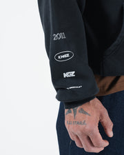 Black BJJ hoodie sleeve detail closeup showing Kingz Originals 2011 arm graphics and ribbed cuff