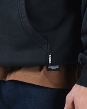 Black BJJ hoodie hem detail closeup showing woven Kingz brand label and ribbed bottom cuff stitching