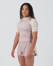 Kingz Terra Women's Rashguard Soil Edition - Full Body 3/4 Front Left Side View Female Athlete Short Sleeve Dusty Rose Mauve Body Cream Beige Raglan Sleeves Crown Logo Circle KINGZ Right Sleeve Text Matching Mauve Hybrid Shorts Women's BJJ