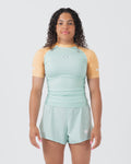 Kingz Terra Women's Rashguard Green Edition - Full Body Front View Female Athlete Short Sleeve Mint Light Green Body Yellow Peach Raglan Sleeves White Crown Logo Chest KINGZ White Text Matching Mint Green Hybrid Shorts BJJ No-Gi