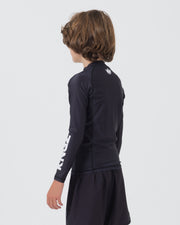 Kingz Kore V2 Youth L/S Rashguard Navy Black - Full Body Right Side Profile View Teen Boy Athlete Long Sleeve Navy Blue Crown Logo Circle Left Chest KINGZ White Vertical Right Sleeve Text Matching Navy Shorts Kids BJJ [color:Black]