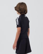 Kingz Kore V2 Youth S/S Rashguard Navy Black - Full Body Right Side Profile View Teen Boy Athlete Short Sleeve Navy Blue KINGZ White Vertical Right Sleeve Text Crown Logo Upper Back Matching Navy Shorts Kids BJJ Minimal Design [color:Black]