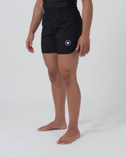 Kingz Kore 2.0 Women's Shorts Black - Full Body Right Side Profile Female Athlete Solid Black Circular Crown Badge Left Thigh White Waistband Stripe Detail Side Split Visible Women's Grappling Shorts No-Gi BJJ Kore Collection [color:Black]