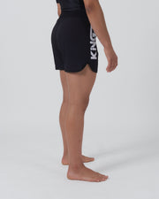 Kingz Kore 2.0 Women's Shorts Black - Full Body Left Side Profile Female Athlete Solid Black Bold Vertical KINGZ White Text Left Side Large Branding Competition Cut Women's Grappling Shorts No-Gi BJJ Kore Collection [color:Black]