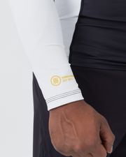 Kingz Ranked Performance V2 L/S Rashguard Navy White - Close Up Wrist Cuff Detail Gold Yellow IBJJF Rank Stripe Three Gold Lines KINGZ KIMONOS EST 2011 Gold Circular Crest Logo White Sleeve Navy Body BJJ Rank Indicator