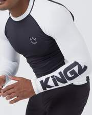 Kingz Ranked Performance V2 L/S Rashguard Navy White - Upper Body Action Pose Right Sleeve Detail KINGZ Large Bold Navy Text White Sleeve Three Stripe Cuff Crown Logo Navy Chest White Side Panel BJJ Training