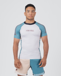 Kingz Flow Rashguard White Teal Blue - Full Body Front View Male Athlete Short Sleeve White Body Teal Blue Raglan Sleeves Dark Navy Collar KINGZ Pink Text Chest Matching Two-Tone Shorts BJJ Training