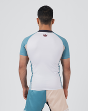 Kingz Flow Rashguard White Teal Blue - Full Body Straight Back View Male Athlete Short Sleeve White Back Panel Teal Blue Raglan Sleeves Dark Navy Collar Pink Crown Logo Center Back Matching Two-Tone Shorts BJJ Training