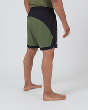 Kingz Trooper Hybrid Shorts Black Olive - Full Body Right-Back Side Profile Male Athlete Two-Tone Black Front Olive Green Back Panel Flag Badge Left Leg Inner Compression Shorts Visible Hem Men's Grappling Shorts No-Gi BJJ