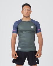 Kingz Draft Rashguard Storm Blue - Full Body Front View Male Athlete Short Sleeve Gray Charcoal Body Blue Raglan Sleeves White Crown Logo Pink KINGZ Labels Crown Badge Black Shorts