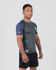 Kingz Draft Rashguard Storm Blue - Full Body Right Side Profile View Male Athlete Short Sleeve Gray Body Blue Raglan Sleeve Crown Logo Pink KINGZ Label Side Accent Stripe KINGZ Badge Shorts