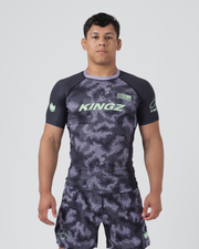 Kingz Viper Rashguard Black Purple - Full Body Front View Male Athlete Short Sleeve Hexagonal Viper Scale Camo Pattern Dark Gray Purple Neck Collar Green Crown Logo KINGZ Green Text Matching Shorts BJJ MMA