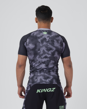 Kingz Viper Rashguard Black Purple - Full Body Straight Back View Male Athlete Short Sleeve Hexagonal Viper Scale Camo Pattern Green Crown Logo Upper Back Black Raglan Sleeves Matching Shorts KINGZ Green Waistband Text BJJ Training