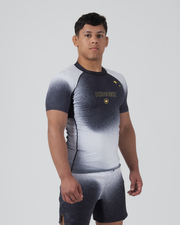 Kingz Galaxy Rash Guard Black White - Full Body Front View Male Athlete Short Sleeve Black To White Ombre Galaxy Spatter Pattern KINGZ Gold Text Gold 4-Point Star Crown Logo Matching Galaxy Shorts BJJ Training Compression Fit